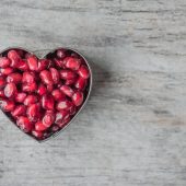 silver heart bowl filled of red pomegranate seeds